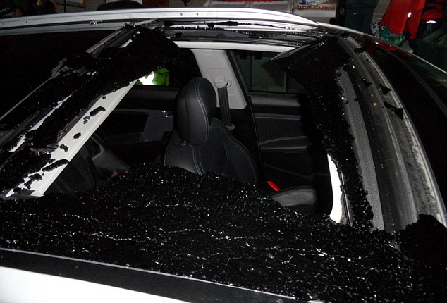 A car with a shattered panoramic sunroof. The roof's glass is completely broken, with shards scattered across the edges and some remaining pieces still attached to the frame.