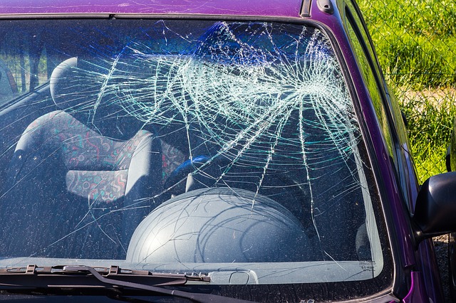 Damaged vehicle windshield from Twin Cities Metro Area in Minnesota. The glass is shattered with a large spiderweb-like crack pattern, primarily concentrated on the driver side.